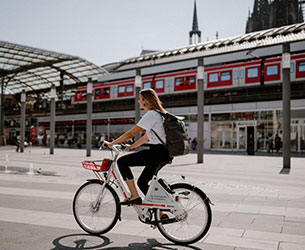 Frau auf Call a Bike Fahrrad an einem Bahnhof