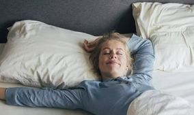 Frau liegt in einem Hotelbett