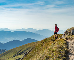 Eine Frau auf Allgaeu Wanderung mit Bergen im Hintergrund.