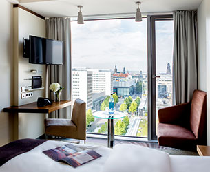 Hotelzimmer des Pullman Dresden mit großem Fenster und Aussicht auf die Stadt