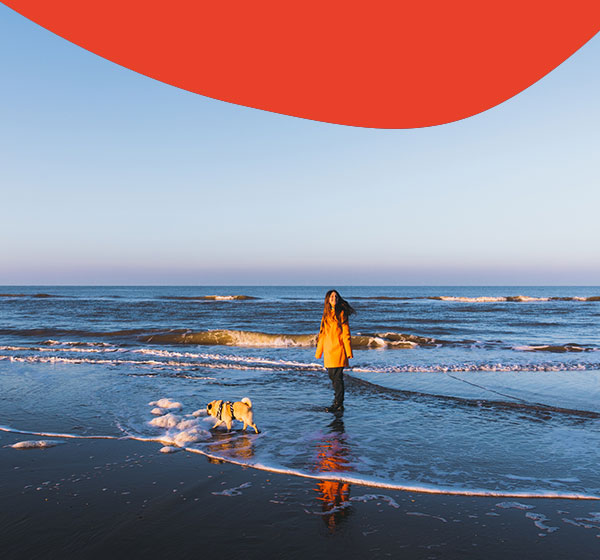 Frau am Strand an der Nordsee mit Hund