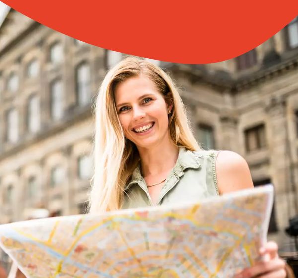 Blonde Frau hält einen Stadtplan und schaut zur Kamera